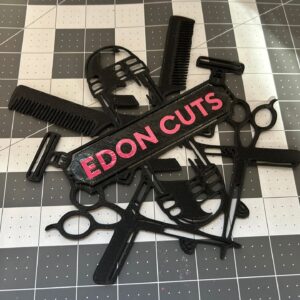 Logo decorativo en negro para barbería impreso en 3D con tijeras, peine, navajas y tubo clásico