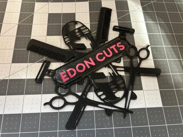 Logo decorativo en negro para barbería impreso en 3D con tijeras, peine, navajas y tubo clásico