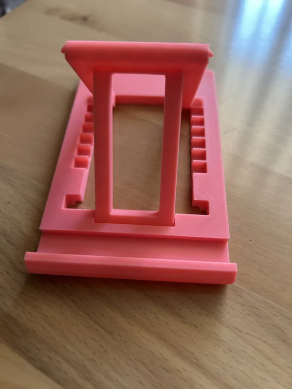 Soporte de móvil impreso en 3D de color rojo sobre superficie de madera