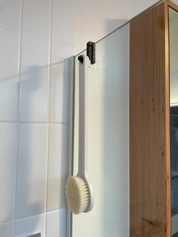 Gancho para mampara de ducha en color blanco colocado sobre vidrio templado